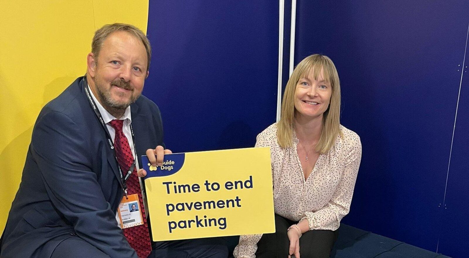 Toby Perkins MP with a campaigner and a guide dog, holding a sign that reads 